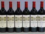 six bouteilles de vin rouge sont alignées sur une table