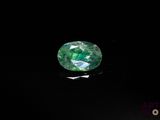 a close up of a green emerald stone on a black surface