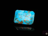 a close up of a turquoise stone on a black surface