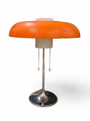 une lampe de table orange avec un pied en métal sur fond blanc
