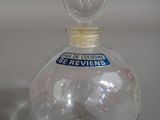 a clear glass bottle with a blue sticker on it