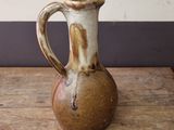 a brown and white vase sitting on a wooden table