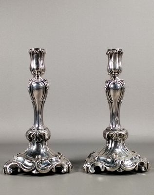 pair of antique silver candlesticks on a grey background