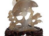 oiseau en jade blanc sculpté sur une branche fleurie, sur fond blanc