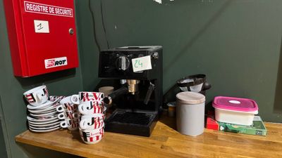 une cafetière et des tasses posées sur un plan de travail dans une pièce