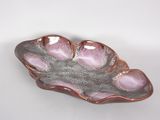 a pink and silver leaf shaped dish on a white table