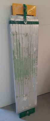 a toilet in a room with a white wall and green paint on it