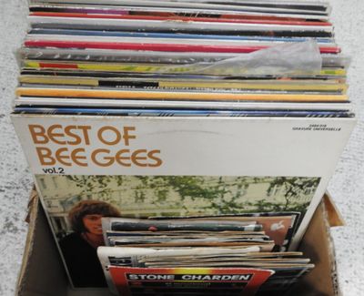 une boîte en carton remplie de disques de toutes sortes, posée par terre
