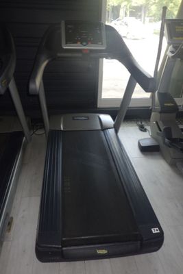 un tapis de course dans une salle de sport, avec une fenêtre en arrière-plan