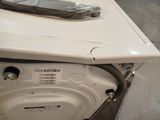 a white washer sitting inside of a room with a bag on top of it