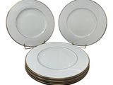 four white plates stacked on top of each other on a white surface