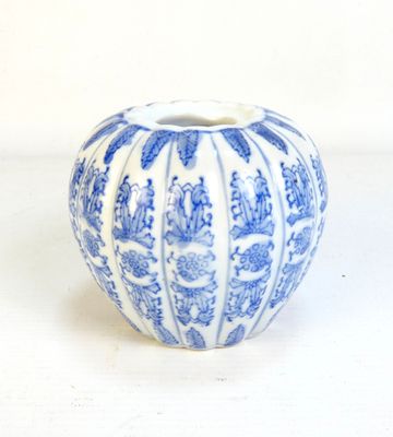 un vase bleu et blanc posé sur une surface blanche
