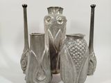 three silver vases sitting next to each other on a white surface