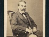 portrait d'un homme en costume-cravate, assis sur une chaise