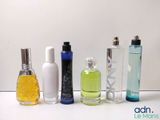 plusieurs types différents de flacons de parfum alignés sur une surface blanche