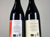 two bottles of red wine sitting next to each other on a table