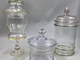 trois bocaux en verre avec leurs couvercles, posés sur une surface blanche