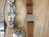 two watches sitting on a wooden table next to each other