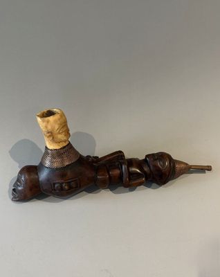 un porte-pipe en bois contenant une pipe, posé sur une table