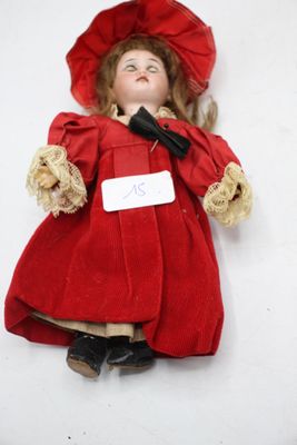 une petite poupée avec une robe rouge et un chapeau rouge