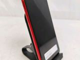 a red and black phone on a stand on a white surface