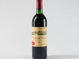 a bottle of red wine sitting on top of a white table