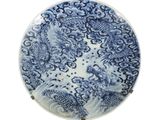 assiette bleue et blanche ornée d'un motif de dragon sur fond blanc