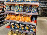 many bags of chips on the shelves in the store