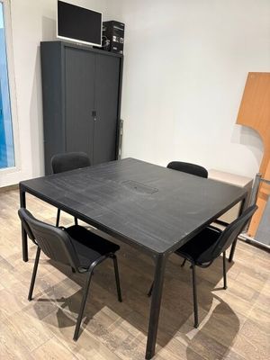 une table et des chaises noires dans une pièce dotée d'une porte-fenêtre coulissante
