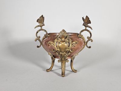 une image représentant un vase rose et doré orné de deux oiseaux