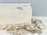 un bloc de marbre blanc posé sur une table, sur lequel se trouvent des pièces de monnaie