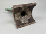 a metal object with a hole in it on a white surface