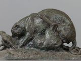 statue of a bull laying down on a rock with a bird in its mouth