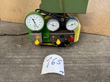 a green machine with two gauges and a sign next to it