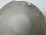 a white bowl with a black handle on a white table