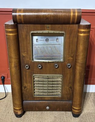 an old radio sitting on top of a carpeted floor next to a red wall