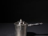 a small silver pot with a handle on a table