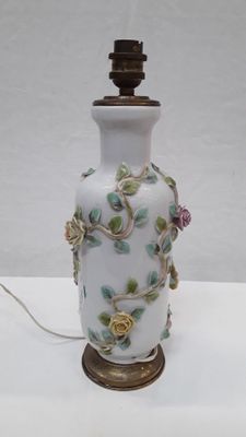a white vase with flowers on it on a table