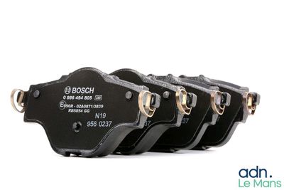 four black brake pads with gold hardware on a white background