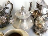plusieurs théières en argent et une tasse de café posées sur une table