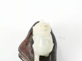 a small figurine of a pig sitting on a piece of wood