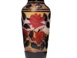 un vase orné d'une feuille rouge sur un fond blanc