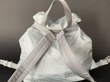 the backpack is white and has a strap on it