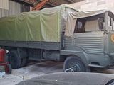 a green truck parked in a garage next to a red tractor