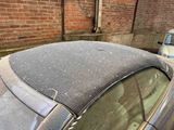 a dirty car parked in front of a brick building