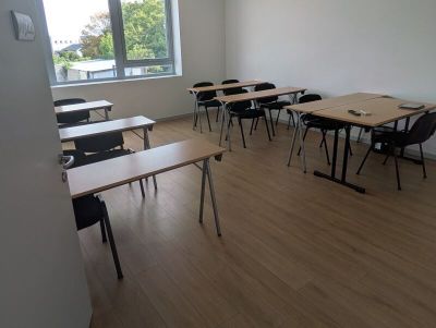 des tables et des chaises dans une salle de classe, avec une grande fenêtre en arrière-plan