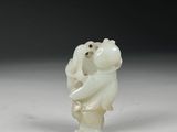 une figurine en jade blanc représentant un ours tenant un bébé dans ses bras
