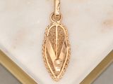 an image of a gold pendant on a marble surface
