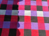 a red, black, and purple checkered blanket on the ground