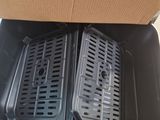 two black grill pans sitting inside of a cardboard box on top of a table